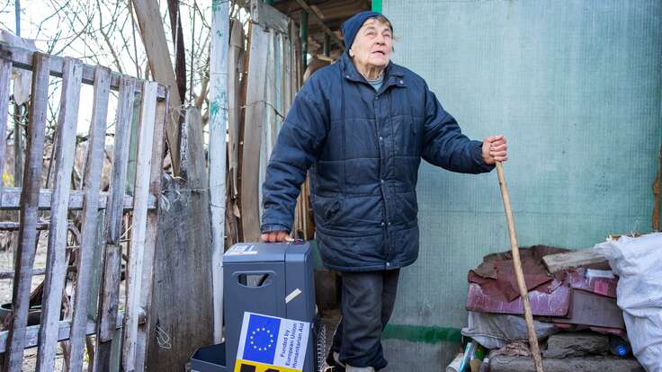 Vira bringing a gas heater supplied by the IRC into her home